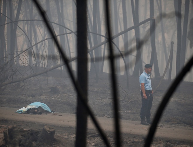 ATTENTION EDITORS - VISUAL COVERAGE OF SCENES OF INJURY OR DEATH A policeman stands near a victim of a forest fire on the IC8 motorway near Pedrogao Grande, in central Portugal, June 18, 2017. REUTERS/Rafael Marchante TEMPLATE OUT