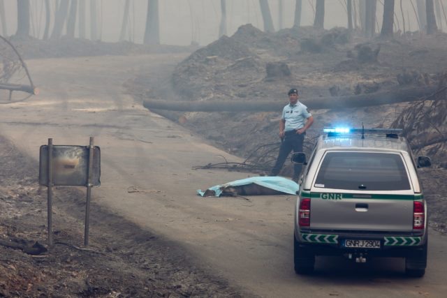 epaselect epa06034888 A Republican National Guard member stays near a unidentified dead body, near the IC8 road beteew Avelar and Pedrogao Grande, central Portugal, 18 June 2017. At least fifty-seven people have been killed in forest fires in central Portugal, with many being trapped in their cars as flames swept over a road on the evening of 17 June 2017. A total of 688 firefighters are providing assistance. EPA/MIGUEL A. LOPES