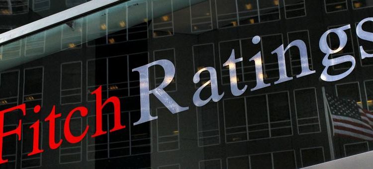 A flag is reflected on the window of the Fitch Ratings headquarters in New York February 6, 2013. REUTERS/Brendan McDermid (UNITED STATES - Tags: BUSINESS)