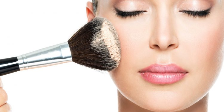 woman  applying dry cosmetic tonal foundation  on the face