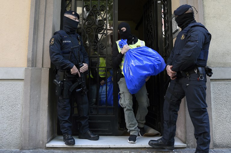 A members of the Catalan Regional Police (Mossos d'Esquadra) carries a garbage bag during the raid of a flat in Barcelona on April 25, 2017 that led to the arrest of four men accused of collaborating with the Islamic militants. Spanish police today arrested four men over their alleged links to suspects arrested in Belgium over their alleged involvement in the Brussels airport and metro attacks last year, officials said.  / AFP PHOTO / LLUIS GENE