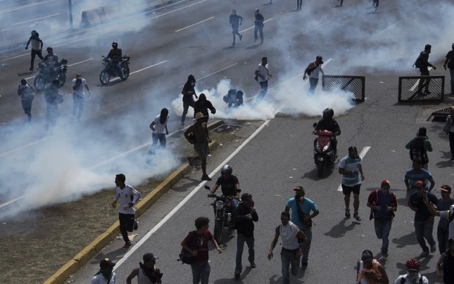 Demonstrators clash with riot police during a march against Venezuelan President Nicolas Maduro, in Caracas on April 19, 2017. Venezuelans took to the streets Wednesday for massive demonstrations for and against President Nicolas Maduro, whose push to tighten his grip on power has triggered deadly unrest that has escalated the country's political and economic crisis. / AFP PHOTO / CARLOS BECERRA