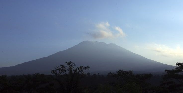 In this Sept. 20, 2017, file photo, Mount Agung volcano is seen at sunrise in Bali, Indonesia. Warnings that a volcano on the Indonesian tourist island of Bali will erupt have sparked an exodus of more than 75,000 people that is likely to continue to swell, according to Indonesia's disaster agency. (AP Photo/Firdia Lisnawati, File)