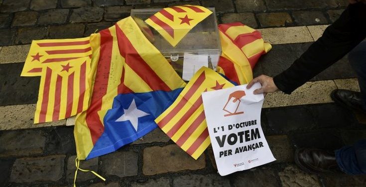 A pro independences supporter holds up a sign calling for the vote close to a mock ballot boxes covered with ''esteleda'' or Catalan pro independence flags in support of the Catalonia's secession referendum, in Pamplona, northern Spain, Sunday, Oct. 1, 2017.   Catalonia's regional government is holding a referendum Sunday on the possibility of breaking away from Spain, despite Spain's Constitutional Court ordering the vote to be suspended and prompting a police crackdown.  (AP Photo/Alvaro Barrientos)