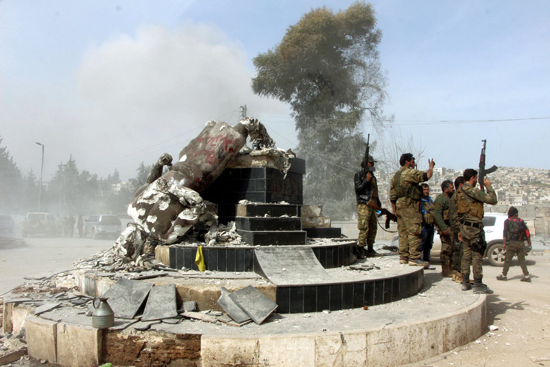 Turkey-backed Free Syrian Army soldiers celebrate around a statue of Kawa, a mythology figure in Kurdish culture, after they have destroyed it in the city center of Afrin, northwestern Syria, early Sunday, March 18, 2018. Turkey's President Recep Tayyip Erdogan said Sunday that allied Syrian forces have taken "total" control of the town center of Afrin, the target of a nearly two-month-old Turkish offensive against a Syrian Kurdish militia, which said fighting was still underway. Erdogan said the Turkish flag and the flag of the Syrian opposition fighters have been raised in the town, previously controlled by the Kurdish militia known as the People's Defense Units, or YPG. (Hasan Kırmızitaş/DHA-Depo Photos via AP)