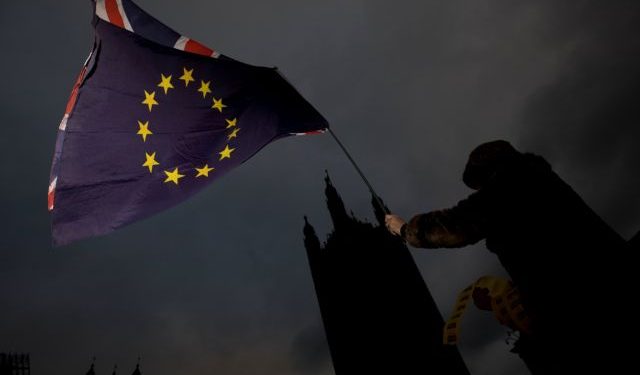 An Anti-Brexit protestor waves EU and Union flags outside the Houses of Parliament in London