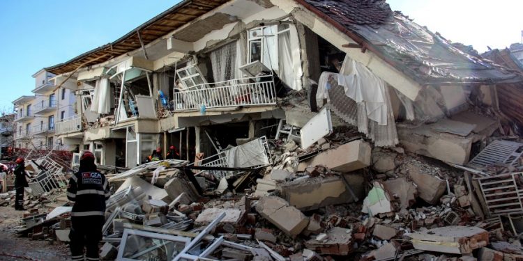 Rescue workers try to reach people under a collapsed building following a strong earthquake in Elazig in the eastern Turkey, Saturday, Jan. 25, 2020. The earthquake rocked eastern Turkey on Friday, causing some buildings to collapse and killing scores of people, Turkish officials said. (IHA via AP)