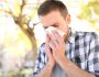 Allergic man sneezing covering nose with wipe