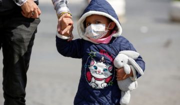 A child wearing a protective face mask walks near the Colosseum, after a decree orders for the whole of Italy to be on lockdown in an unprecedented clampdown aimed at beating the coronavirus, in Rome