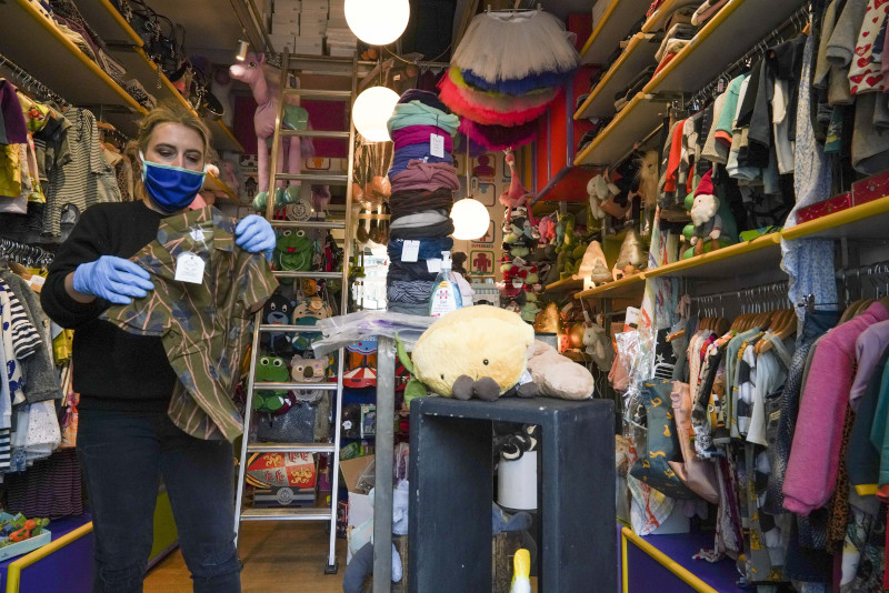 Camilla Cocchi wears a face mask and gloves as she sorts out clothing in her children's clothes shop after it was allowed to reopen following lockdown measures to contain the spread of Covid-19, in Rome, Tuesday, April 14, 2020. In Italy, bookstores, stationary stores and shops selling baby clothes and supplies were allowed to open nationwide on Tuesday, provided they could maintain the same social-distancing and sanitary measures required in supermarkets. The new coronavirus causes mild or moderate symptoms for most people, but for some, especially older adults and people with existing health problems, it can cause more severe illness or death. (AP Photo/Andrew Medichini)