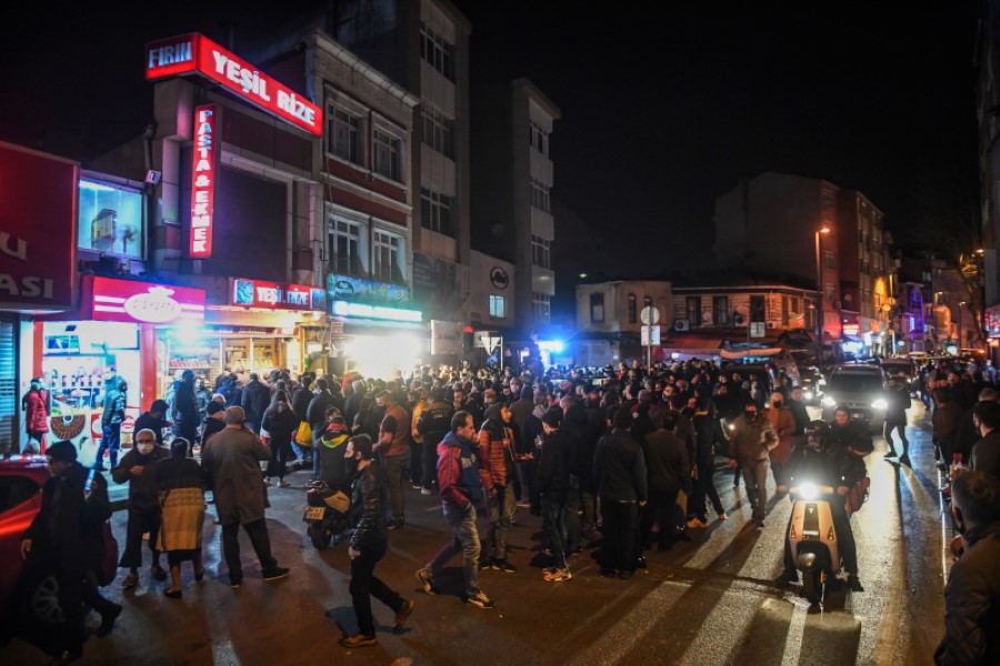 People gather around a convenience store in central Istanbul to buy groceries, following weekend curfew announcement, late Friday, April 10, 2020. Turkey has announced a two-day curfew in 31 of Turkey's largest cities as it tries to curb the spread of the coronavirus outbreak. Minutes after the announcement, which goes into effect at midnight (21:00 gmt) Friday, people rushed to get in some last-minute shopping and lines formed outside grocery and convenience stores. (AP Photo)