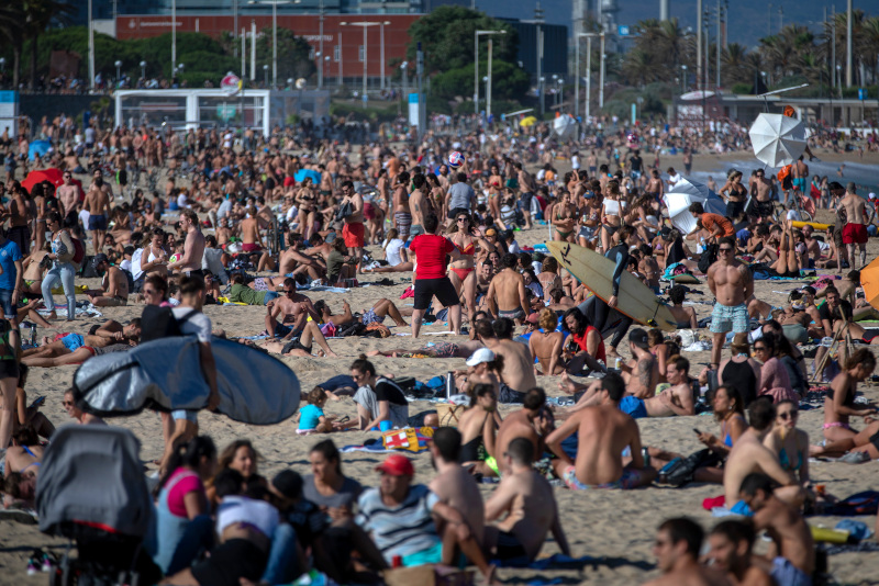 People enjoy the warm weather on the beach in Barcelona, Spain, Friday, June 12, 2020. Spanish government has announced that the northwestern region of Galicia will move next week to what the government calls "the new normal," when some rules, such as wearing face masks when social distancing is not possible, will remain in place. (AP Photo/Emilio Morenatti)