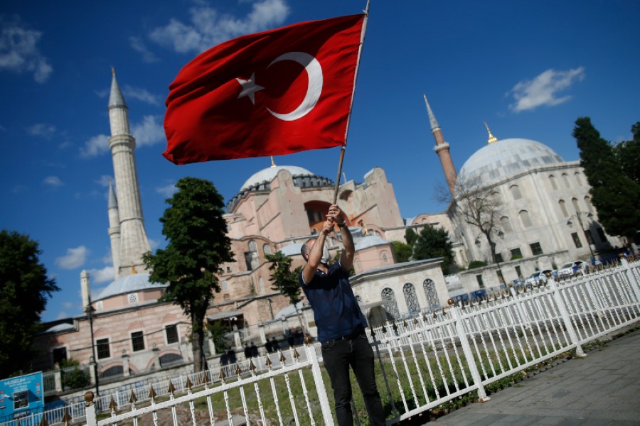 A man waves a Turkish flag outside the Byzantine-era Hagia Sophia, one of Istanbul's main tourist attractions in the historic Sultanahmet district of Istanbul, following Turkey's Council of State's decision, Friday, July 10, 2020.Turkey's highest administrative court issued a ruling Friday that paves the way for the government to convert Hagia Sophia - a former cathedral-turned-mosque that now serves as a museum - back into a Muslim house of worship. The Council of State threw its weight behind a petition brought by a religious group and annulled a 1934 cabinet decision that changed the 6th century building into a museum. (AP Photo/Emrah Gurel)