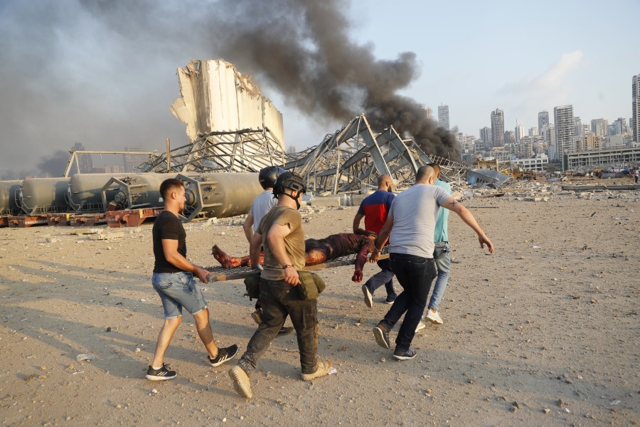 Civilians carry a victim at the explosion scene that hit the seaport, in Beirut Lebanon, Tuesday, Aug. 4, 2020. Massive explosions rocked downtown Beirut on Tuesday, flattening much of the port, damaging buildings and blowing out windows and doors as a giant mushroom cloud rose above the capital. Witnesses saw many people injured by flying glass and debris. (AP Photo/Hussein Malla)
