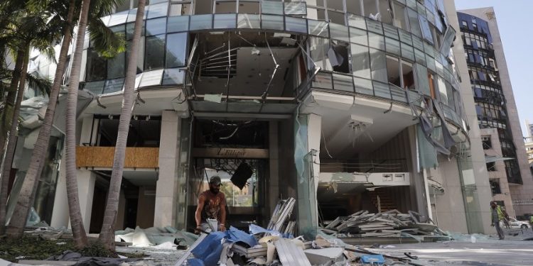 A worker removes broken windows and debris from one of damaged streets, after an explosion hit the seaport of Beirut, Lebanon, Wednesday, Aug. 5, 2020. Residents of Beirut awoke to a scene of utter devastation on Wednesday, a day after a massive explosion at the port sent shock waves across the Lebanese capital, killing at least 100 people and wounding thousands. (AP Photo/Hussein Malla)