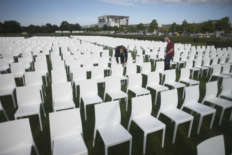 Activists set up chairs at the 'Platz der Republik' in with the chancellery in the background, as part of the nationwide anti-racist action days of 'We'll Come United' in Berlin, Germany, Monday, Sept. 7, 2020. About some 13.000 chairs will be placed here in front of the parliament building, symbolising the people who currently live in Moria migrants camp in Greece. (AP Photo/Markus Schreiber)