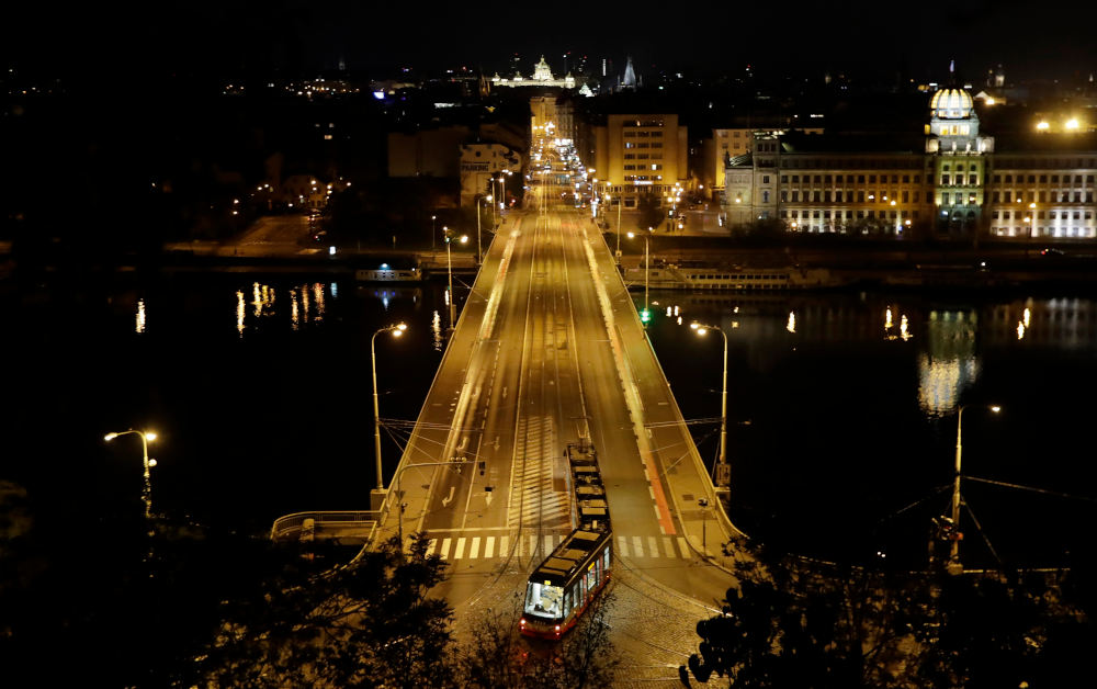 A tram turns to an empty bridge after the night curfew has started in Prague, Czech Republic, Wednesday, Oct. 28, 2020. Starting on Wednesday, the government has imposed a nation-wide curfew between 9 p.m. and 4:59 a.m. It doesn't apply for people traveling to work and also for those walking their dogs within 500 meters (547 yards) from their homes. (AP Photo/Petr David Josek)