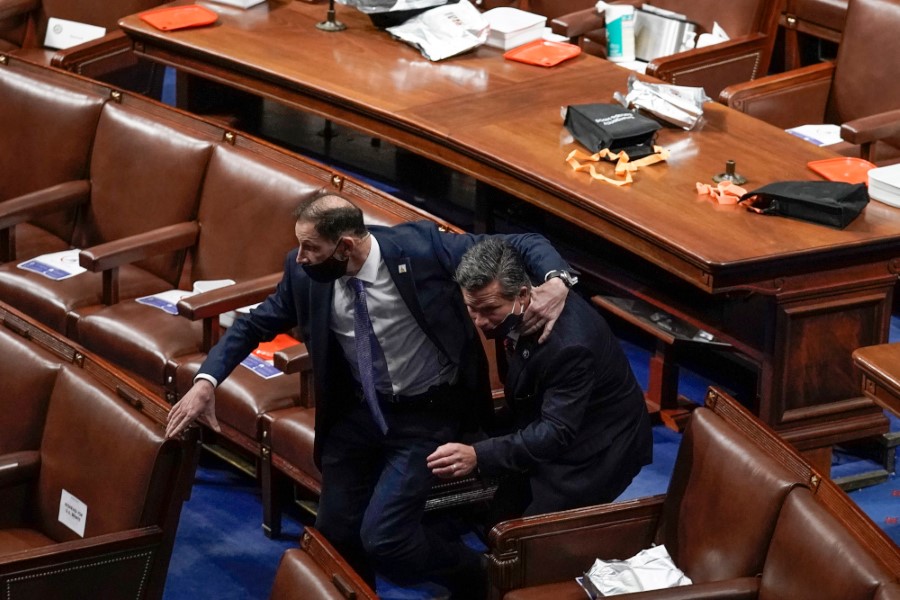 House of Representatives members leave the floor of the House chamber as protesters try to break into the chamber at the U.S. Capitol on Wednesday, Jan. 6, 2021, in Washington. (AP Photo/J. Scott Applewhite)