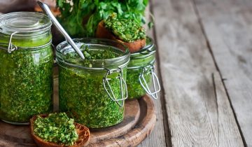 Homemade cilantro pesto in jars on wooden background