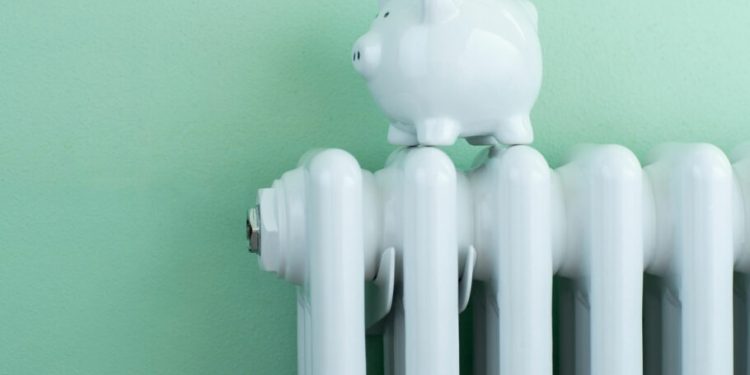 Piggy Bank Balanced On Radiator To Illustrate Energy Costs