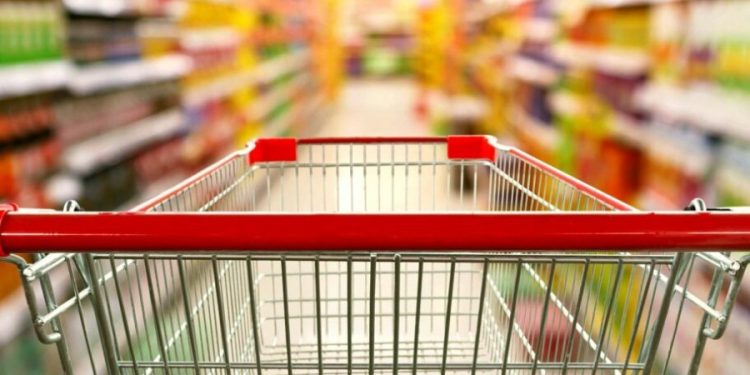 Supermarket aisle interior blur background with empty red shopping cart
