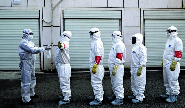 Volunteers in protective suits are being disinfected in a line in Wuhan, the epicentre of the novel coronavirus outbreak, in Hubei