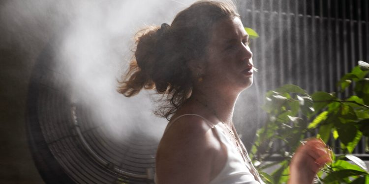 A woman cools off in front of a water vapor fan during a heatwave in Madrid, Spain, Saturday, Aug. 14, 2021. Temperatures were set to hit a maximum of 46 degrees Celsius in Spain on Saturday, as the country sweltered on the hottest day of the year so far. (AP Photo/Andrea Comas)