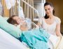 Beautiful woman looking at man lying on bed in hospital