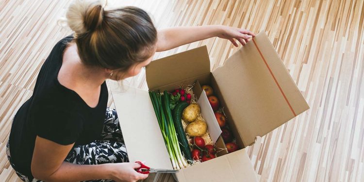 woman opening a vegetable delivery box at home