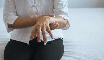 Elderly woman suffering with parkinson's disease symptoms on hand