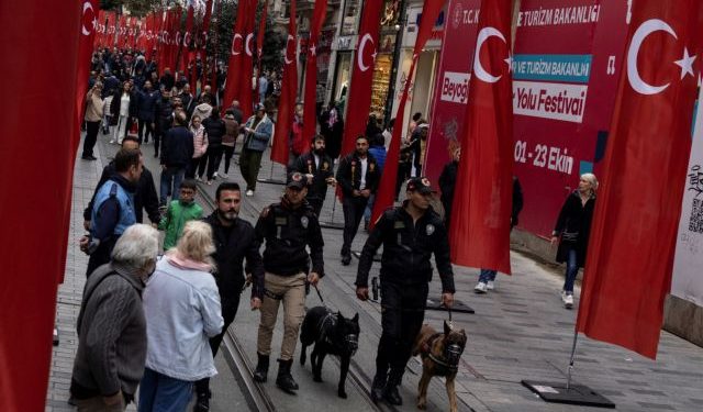 People and police officers walk along Istiklal Avenue, decorated with Turkish national flags after Sunday's blast killed six and wounded dozens, in Istanbul, Turkey, November 14, 2022. REUTERS/Umit Bektas