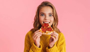 Excited,Beautiful,Blonde,Girl,Eating,Pizza,At,Camera,Isolated,Over