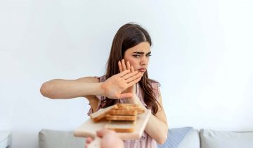 Cropped shot of a young woman on a gluten free diet is saying no thanks to white bread. Woman refusing to eat white bread. Gluten intolerance concept. Health care and medicine concept. Copy space.
