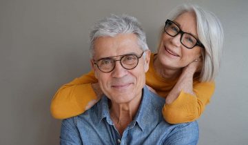 Portrait of relaxed fun senior couple wearing glasses on background