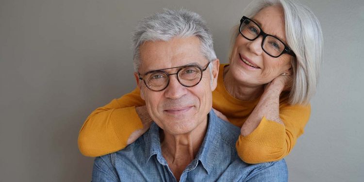 Portrait of relaxed fun senior couple wearing glasses on background