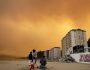 People visit the beach as a forest fire burns part of Tome, Chile, February 3, 2023. REUTERS/Juan Gonzalez