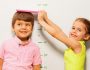 Boy and girl measure height by wall scale at home