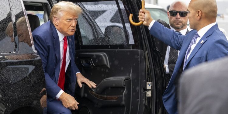 Former President Donald Trump exits his vehicle to walk over to speak with reporters before he boards his plane at Ronald Reagan Washington National Airport, Thursday, Aug. 3, 2023, in Arlington, Va., after facing a judge on federal conspiracy charges that allege he conspired to subvert the 2020 election. At right his valet Walt Nauta. (AP Photo/Alex Brandon)