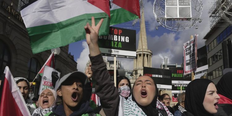 Protesters hold placards during a pro Palestinian demonstration in London, Saturday, Oct. 14, 2023, in support of Palestinians caught up in the war between Israel and Hamas. (AP Photo/Kin Cheung)
