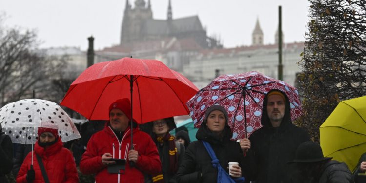 Mourners observe a minute of silence for the victims of mass shooting in front of the building of Philosophical Faculty of Charles University in downtown Prague, Czech Republic, Saturday, Dec. 23, 2023. A lone gunman opened fire at a university on Thursday, killing more than a dozen people and injuring scores of people. (AP Photo/Denes Erdos)