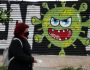 A woman wearing a face mask to prevent the spread of coronavirus, walks in front of a graffiti by artists Open/Esem in Athens, Tuesday, Jan. 12, 2021. Greece has extended a two-month lockdown till Jan. 18, and announced plans to increase the number of people getting COVID-19 vaccines. (AP Photo/Thanassis Stavrakis)