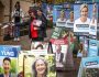 Volunteers hand out voting cards next to election candidate posters outside a pre-polling centre in Sydney on May 2, 2025, ahead of Australias federal election scheduled for May 3. (Photo by DAVID GRAY / AFP)