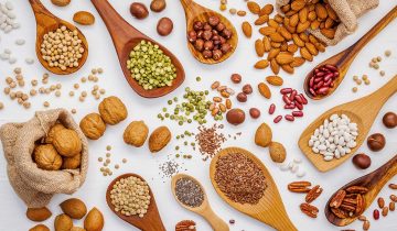 Various legumes and different kinds of nuts in spoons. Walnuts k
